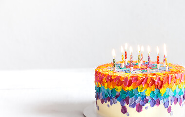 Colorful handmade birthday cake with burning candles copy space.