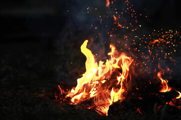 Burning red hot sparks fly from big fire. Burning coals, flaming particles flying off against black background.