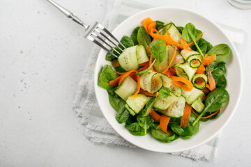 Canvas Print - Green vegan salad from spinach leaves, cucumbers and carrots. Top view on white concrete table.