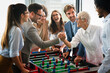 Business people having great time together. Colleagues playing table football in office.