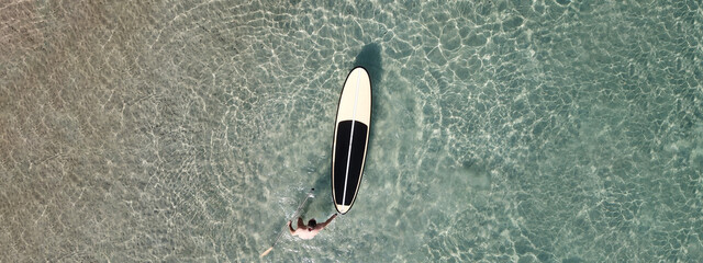 Aerial drone top down ultra wide photo of Stand Up Paddle surf board or SUP board as seen in tropical exotic beach shore