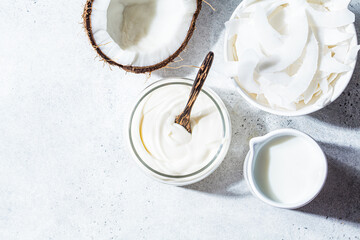 Wall Mural - Vegan coconut products - milk, yogurt and chips, white background, top view. Coconut food concept.