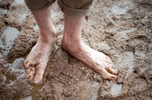 Bare Dirty Male Feet Standing On Wet Ground. Homelessness, Poverty, Economic Crisis Concept