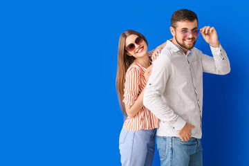 Poster - Young couple with stylish sunglasses on color background