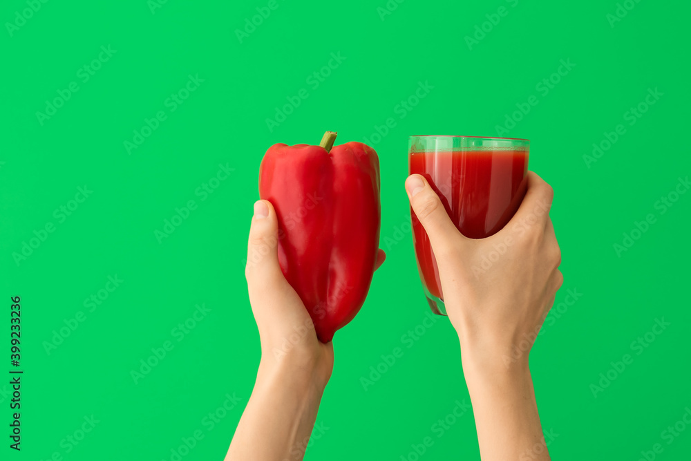Hands with glass of pepper juice on color background