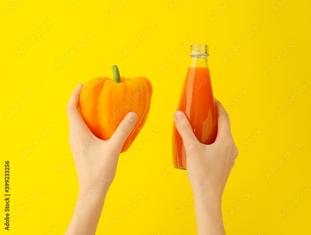 Hands with bottle of pepper juice on color background
