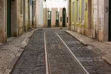 Empty Narrow Cobblestone Street Or Alley With Tramway Rails, Lisbon, Portugal