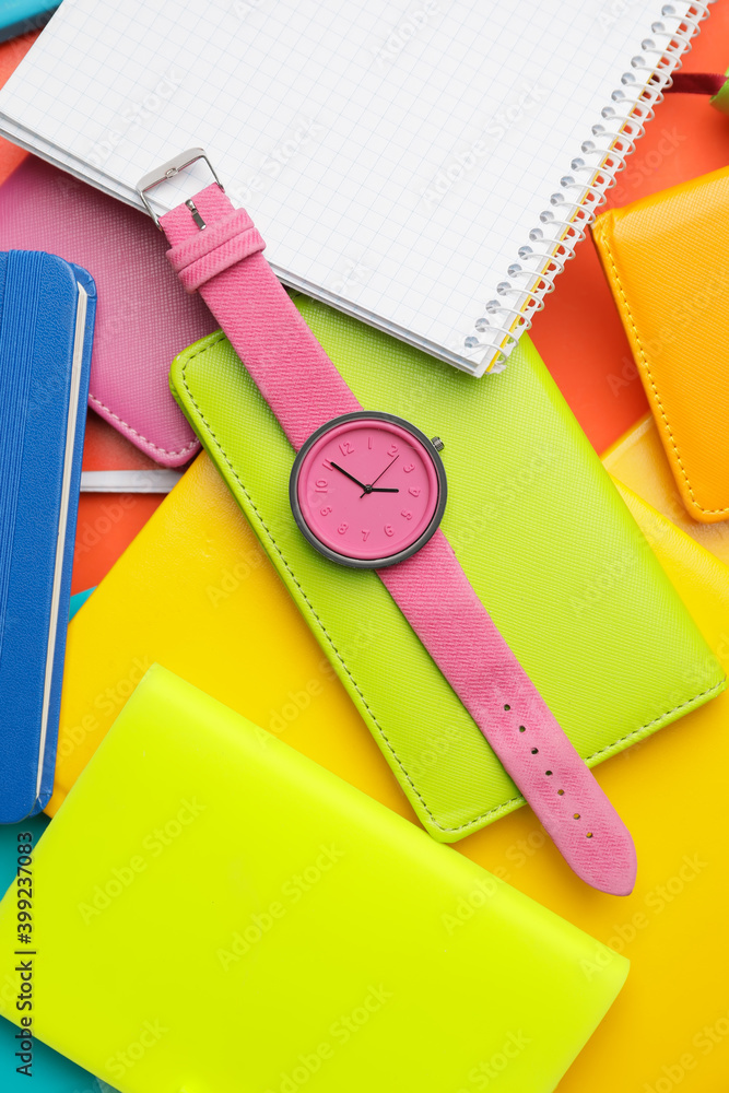 Wrist watch with notebooks on color background background