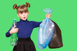 © Svetlana - Little ecologist girl with confused funny face holding trash bags with plastic bottles isolated on green background