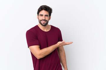 Wall Mural - Young handsome man with beard over isolated white background presenting an idea while looking smiling towards