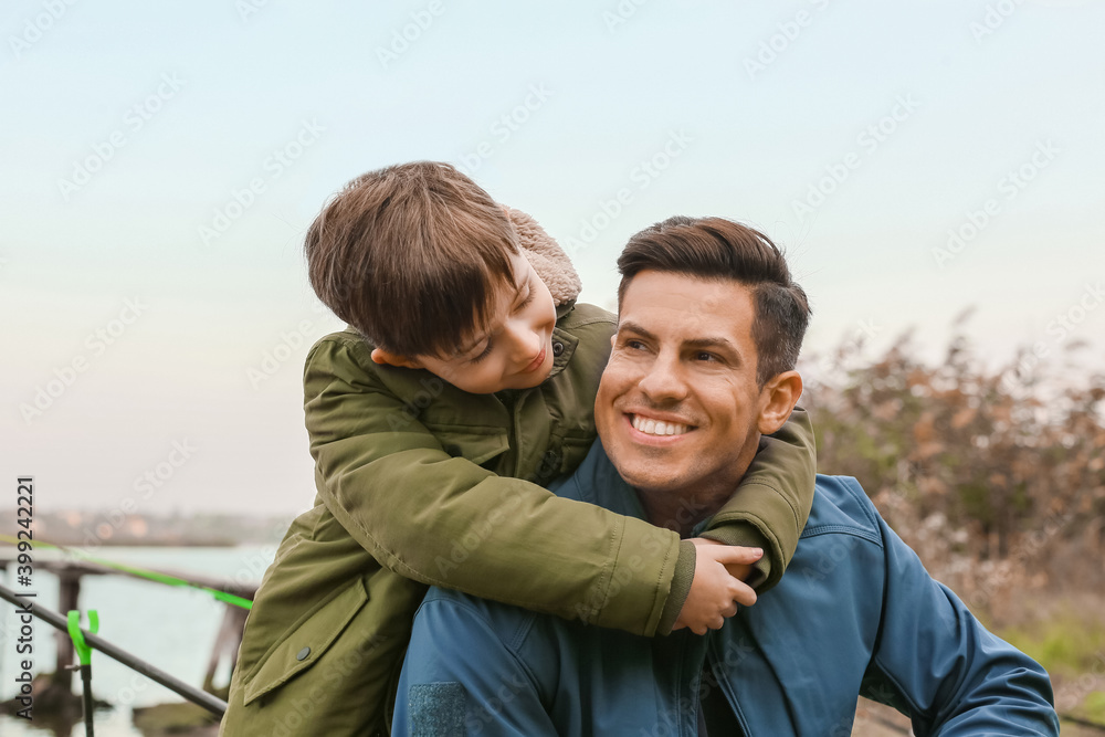 Little boy and his father fishing on river