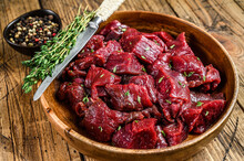 Raw Cut Wild Venison Meat For A Goulash In A Wooden Plate. Wooden Background. Top View