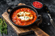 Baked hake white fish with tomato in a pan. Black background. Top view