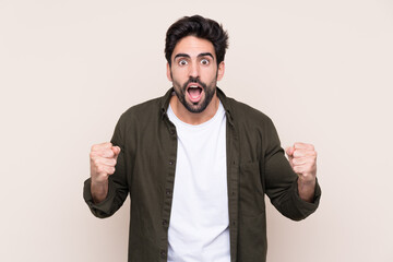 Wall Mural - Young handsome man with beard over isolated background celebrating a victory in winner position