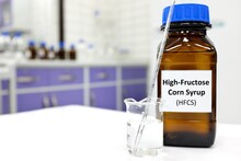 Selective Focus Of High-fructose Corn Syrup Or Hfcs Food And Beverage Sweetener In Dark Brown Glass Bottle Inside A Laboratory.