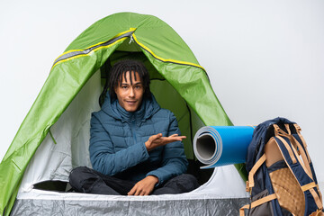 Sticker - Young african american man inside a camping green tent presenting an idea while looking smiling towards