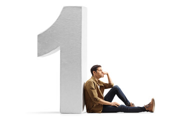 Sticker - Sad young man in casual clothes sitting on the floor and leaning on a big number one