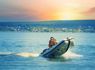 Wall Mural - man drives an inflatable motor boat in lake or sea