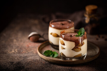 Traditional Italian dessert tiramisu in a glass on on dark background