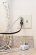 © Mint Images - Cords plugged into electrical socket or outlet and telephone cable.