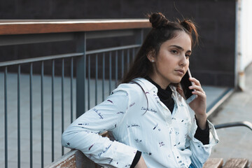 woman waiting for the bus, looking at the mobile phone, sitting on a bench