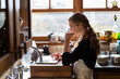 © Mint Images - Teenage girl in a kitchen following a baking recipe on a laptop.
