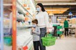 Authentic shot of mother and son wearing medical masks to protect themselves from disease while shopping for groceries together in supermarket.