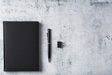 Wall Mural - Black Notepad with a black pen on a gray background