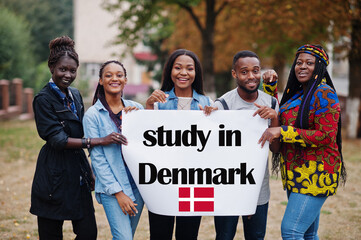 Wall Mural - Study in Denmark. Group of five african college students on campus at university yard hold white blank. Abroad countries for student concept.