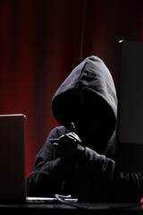 international hacker in black pullover and black mask trying to hack government on a black and red b