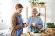 Senior woman with caregiver or healthcare worker indoors, preparing food.