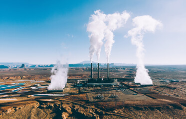 Big industrial factory with tall pipes and emitting toxic smoke