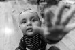 © Valmedia - Black and white portrait shot of playful and curious little cheeky baby boy, playing at home while stretching hand forwards towards camera as to grab it
