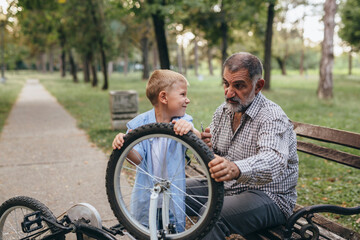 Wall Mural - boy with his grandfather riding bike public park