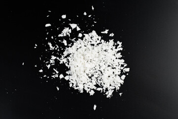 Wall Mural - a pile of poured white artificial synthetic snow on a black background