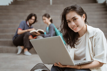 Wall Mural - Portrait happy students holding laptops with friends in the background