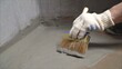 Demonstration of the painted surface with a waterproof paint by cushion and brush. The master applies waterproofing with a brush.