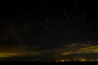 © Ken - Geminid Meteor Shower with jet crossing path. Clouds, city lights in distance
