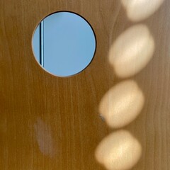 Pattern of light created by sunlight falling on the back of a curved piece of wood with a hole top right and an out of focus object behind, making an interesting abstract background