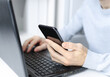 © Юлия Черкасова - A man is working on a laptop. Dial a message on the phone. Business concept, working at home.