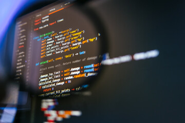 program code on computer display in magnifying glass. close-up