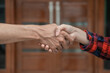 close up of male and female hands shaking hands against the background of the door of the house