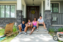 Portrait Of Parents And Children Sitting On Front Porch Steps