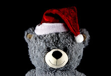 Teddy Bear Wearing Christmas Santa Hat On A Black Background