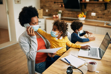 Wall Mural - Happy African American mother working at home during coronavirus pandemic.