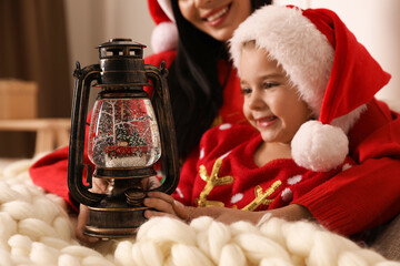 Poster - Mother and daughter playing with decorative snow globe at home, closeup