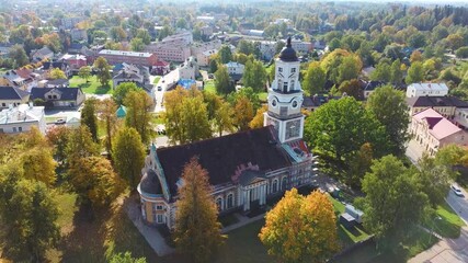 Wall Mural - Old Aluksne Lutheran Church in Colorfull Autumn Park With Golden Cock Statue on the Top of Tower. Aluksne City Latvia. Aerial Dron Shot