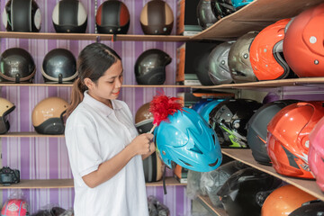 woman shop assistant stands cleaning a helmet with a duster in the helmet shop