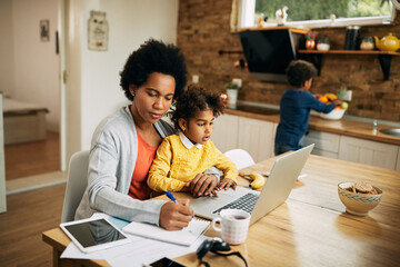 Wall Mural - African American single mother with two kids working at home.