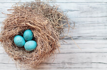 Real Nest With Blue Speckled Colored Bird Eggs On A Rustic White Wooden Background. Top View, Flat Lay. Selective Focus With Blurred Background.